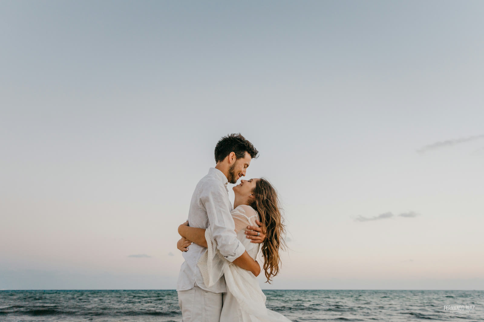 Pareja de boda abrazándose en la playa al atardecer