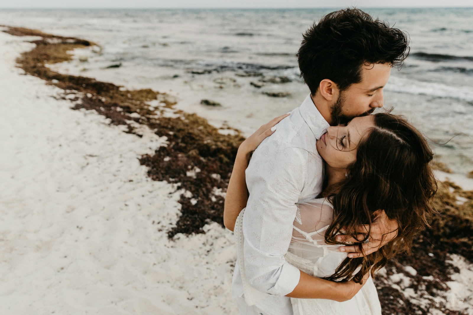 Pareja de boda abrazándose en la playa
