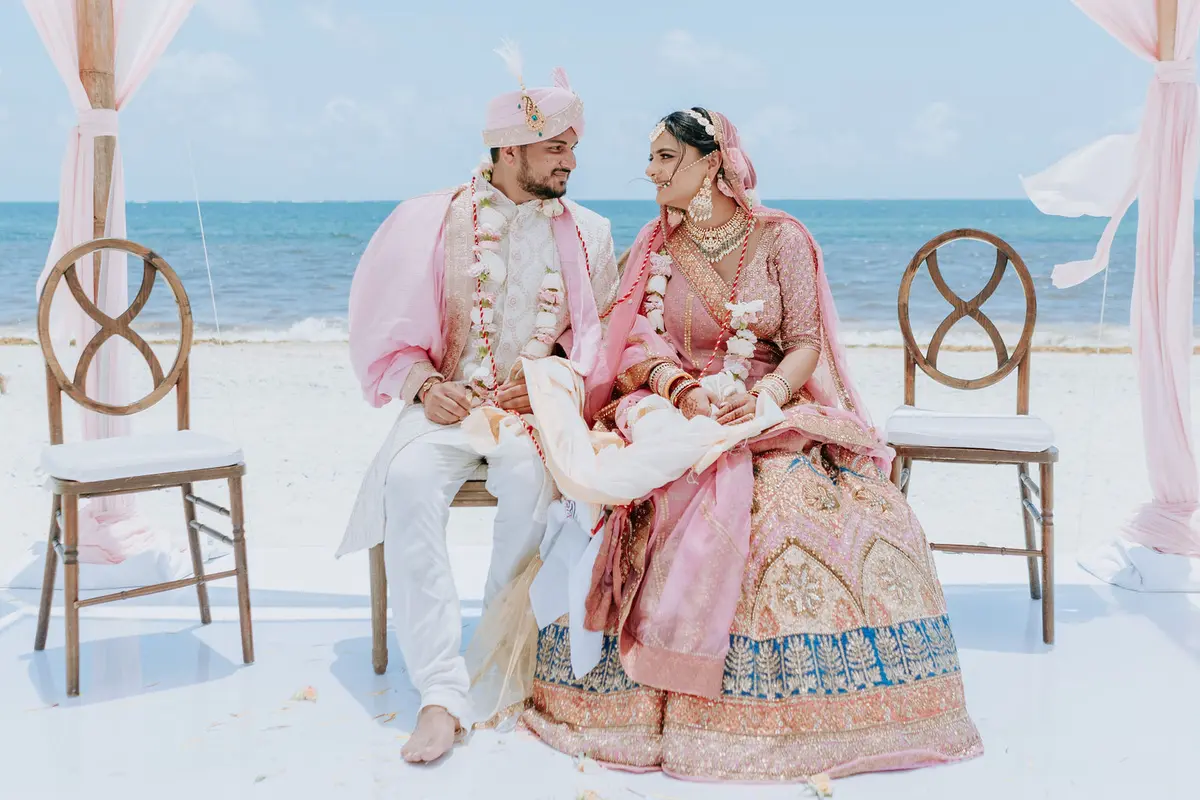 Boda hindú en Royalton Riviera Cancún, el día de la boda: pareja sentada frente al mar.