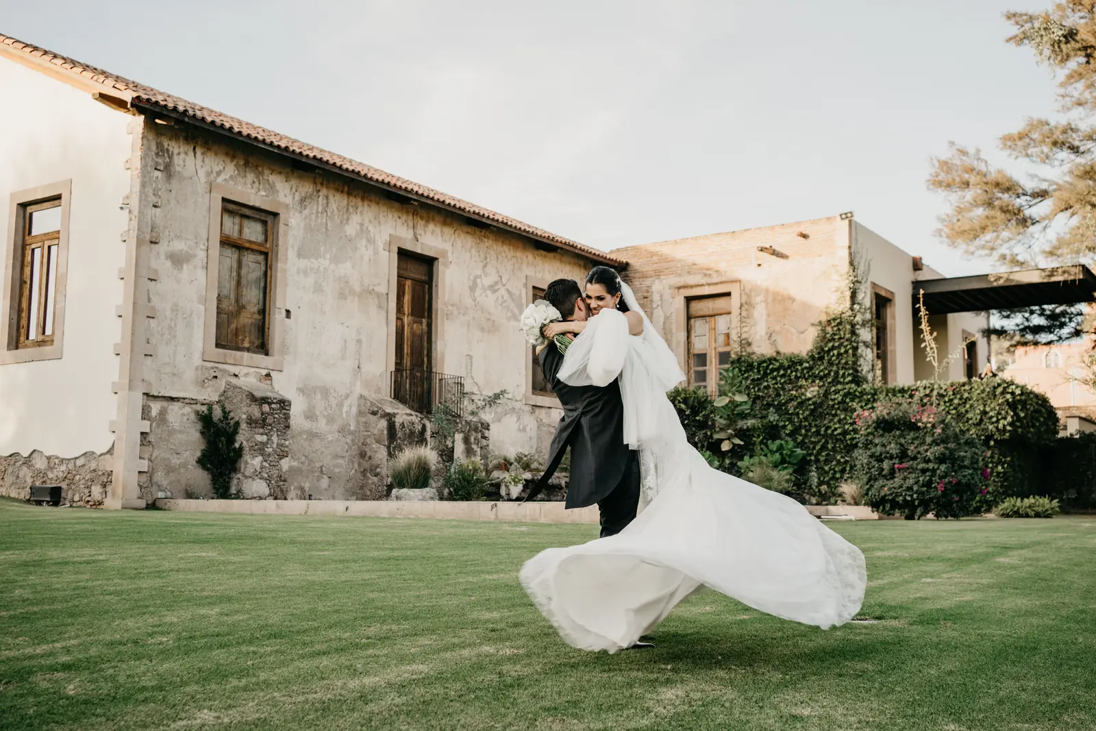 Groom lifting and spinning the bride in a garden