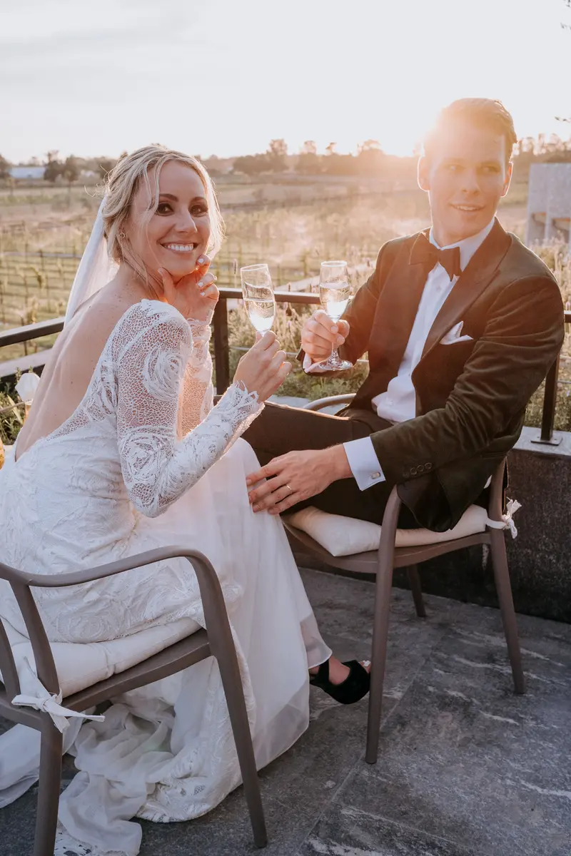 Kelly and Marlon toasting with champagne at golden hour, vineyard rows behind them at Viñedo San Francisco