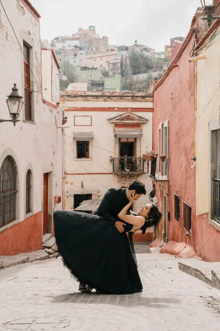 Romantic dip kiss in a terracotta-walled Guanajuato alley during a destination engagement session.