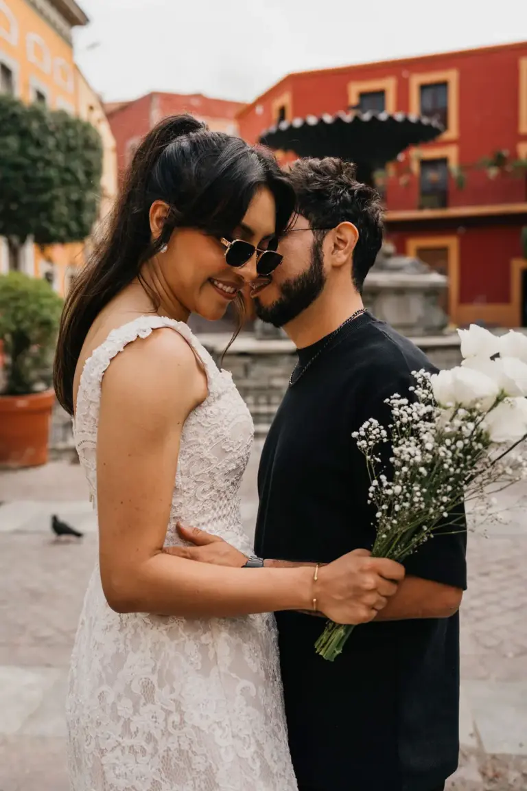 Couple forehead to forehead holding a baby's breath bouquet in a bright, colorful Guanajuato plaza.
