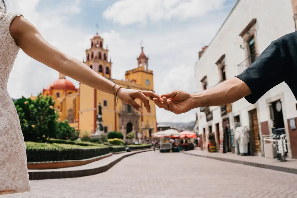 Ella llevando de la mano a su pareja hacia la Basílica amarilla de Guanajuato, la iglesia enmarcada entre los dos