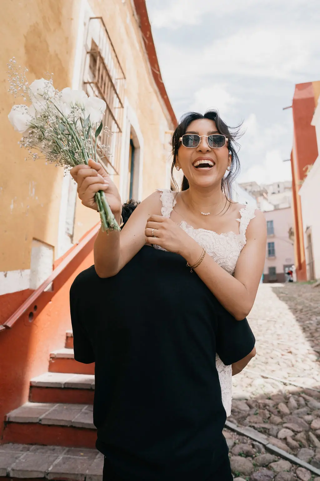 Ella riendo con alegría mientras sopla un ramo de gypsophila en un callejón colorido de Guanajuato