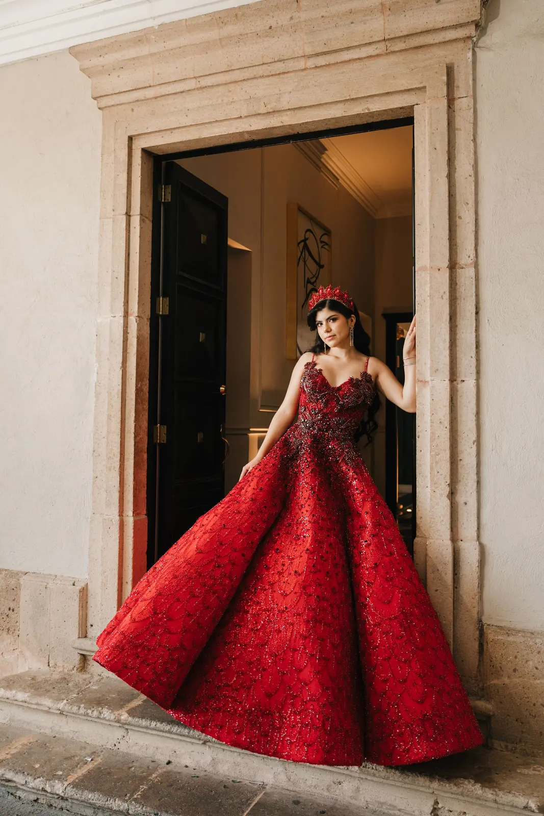 Quinceañera con vestido rojo en el marco de una puerta de cantera